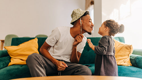 Playful dad giving his daughter a kiss at home