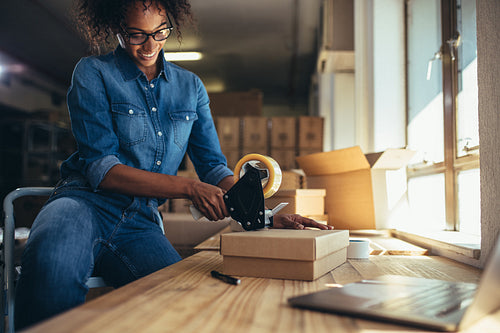 Entrepreneur packing parcel using tape dispenser