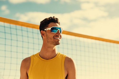 Happy male athlete playing beach volleyball under a clear sky at a coastal location