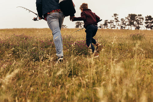 Father and son going for fishing holding fishing rods