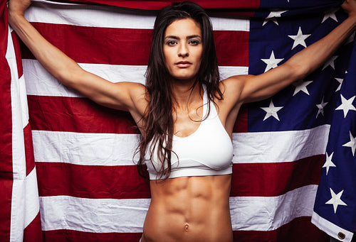 Muscular young woman holding american Flag