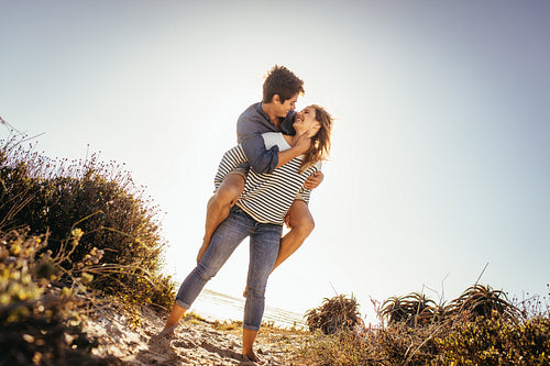 Woman carrying her boyfriend on her back at a beach