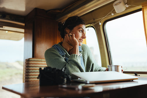 Woman traveling in a van, working at a cozy desk by the window