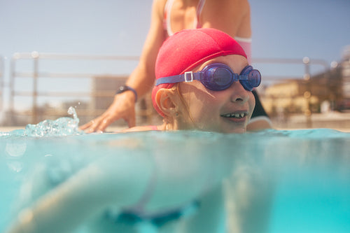 Cute girl learning to swim with coach