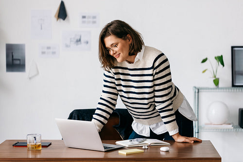 Woman working on laptop in creative office workspace with focused business planning