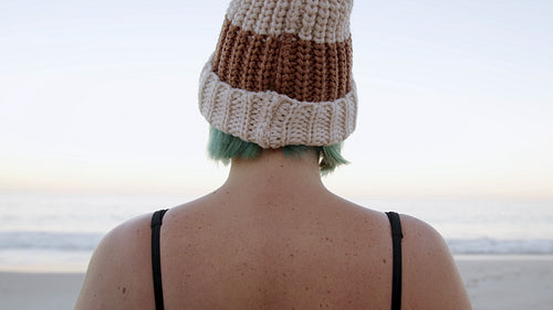 Happy woman swith woolly hat standing on the beach