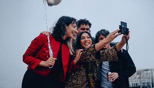 Friends taking a selfie together while celebrating outdoors
