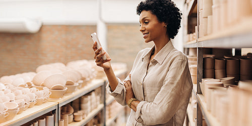 Female entrepreneur reading a text message in her ceramic store