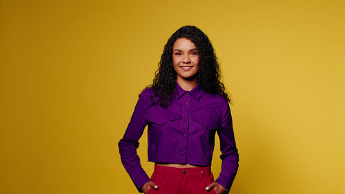 Young woman smiles and poses on yellow background