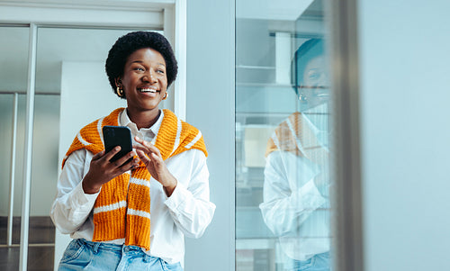 African-American marketing specialist enjoying a break holding a smartphone and smiling brightly