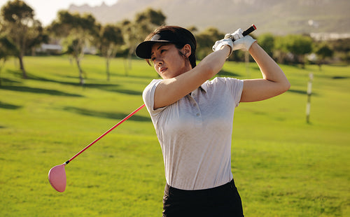 Portrait of Asian woman playing golf on a sunny day with green golf course background