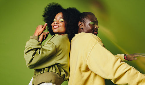 Back-to-back friends dance in the studio with stylish youthful confidence