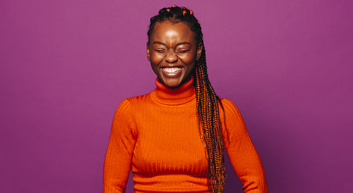 Confident black woman with purple background, stylish two tone braids and colorful makeup