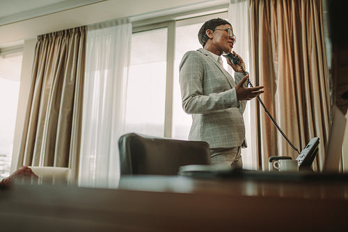 Businesswoman talking over landline phone from hotel room