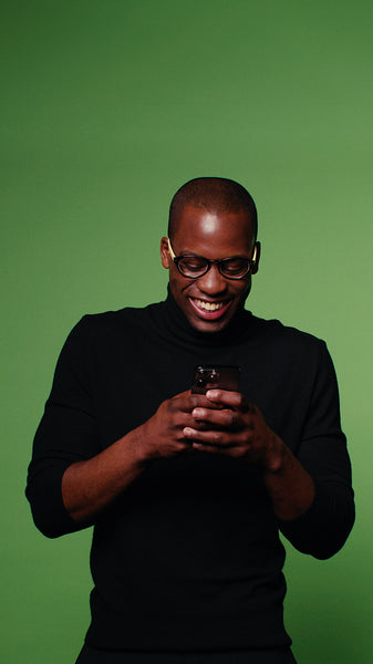 Man laughs at phone on green screen background