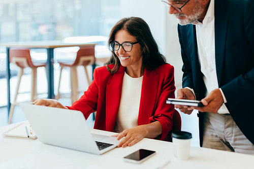Business professionals analyzing data together on a laptop in the office