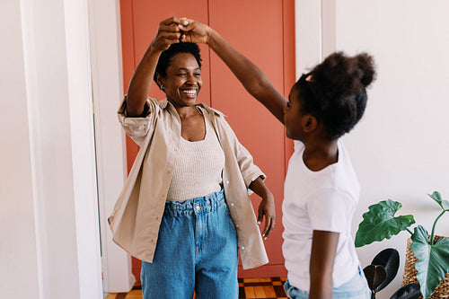 Happy mother dancing with her young daughter at home