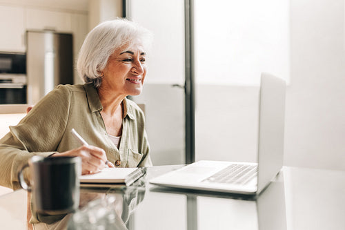 Mature businesswoman attending a video conference in her home of