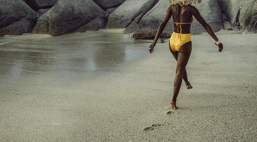 African woman in bikini walking on the beach