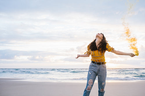 Woman with smoke grenade at the beach