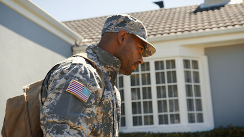Patriotic American soldier returns home from military deployment, carrying a backpack and dressed in camouflage clothing