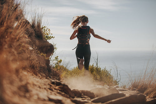 Female running over rocky trails on the hillside.