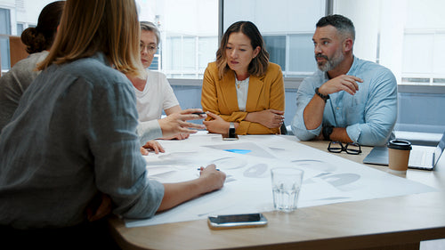 Business team meeting: Design architects sitting around a table discussing blueprints