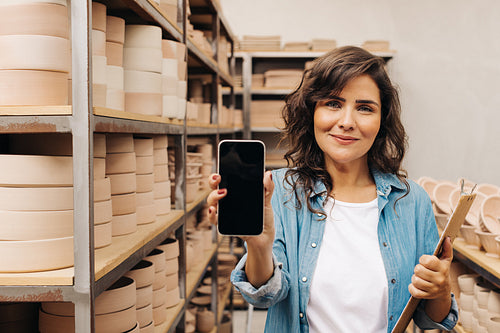 Ceramic shop owner showing a blank smartphone screen in her store