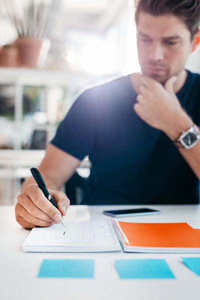 Businessman writing down important notes in office diary