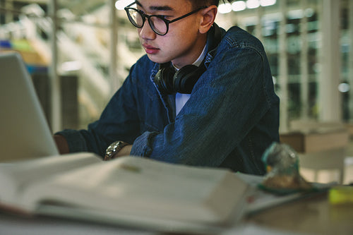 Student sitting in library with laptop in college