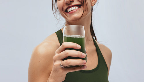 Woman smiling and holding superfood drink in studio