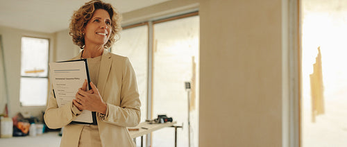 Happy female homeowner holding the paperwork for a home renovation contract