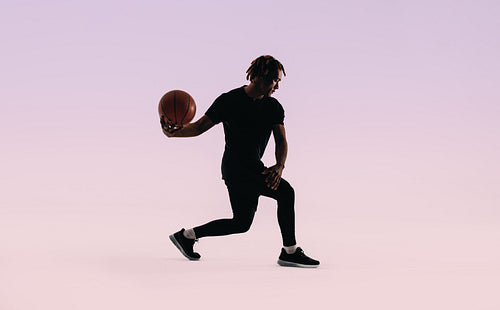Dynamic basketball player showcasing agile moves on pink background