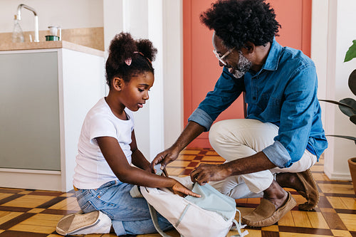 Happy father and daughter packing school bag together