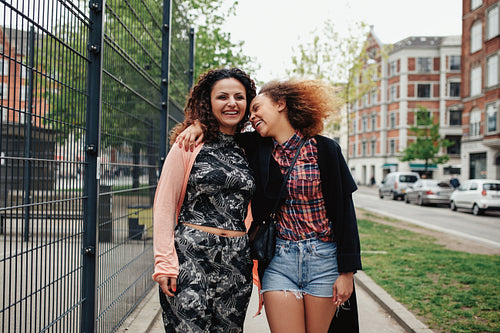 Happy young women walking along city street