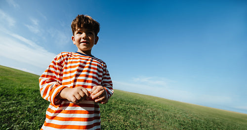Boy in striped shirt outdoors on grassy field