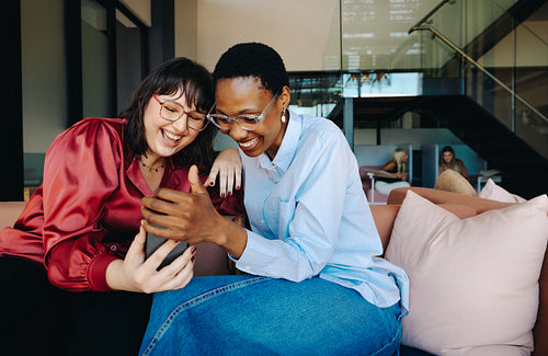 Two young women joyfully enjoying a moment together on a sofa