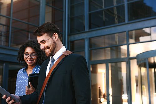 Businesspeople walking out of office building with digital tablet