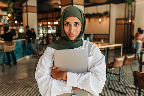 Portrait of a young Muslim woman looking at the camera in a cafe