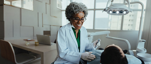 Mature female dentist smiles with patient during consultation in clinic