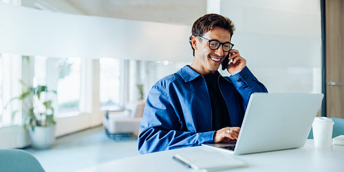 Man on phone at laptop in office