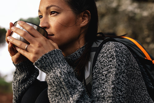 Young female hiker drinking coffee