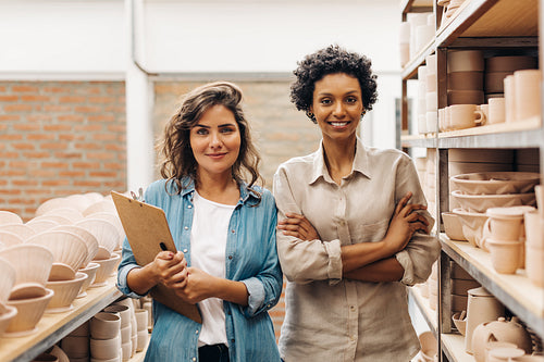 Two successful female ceramists smiling at the camera in the store