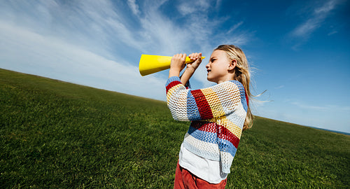 Girl imagining adventures with pretend telescope outdoors