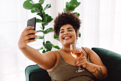 Woman taking selfie with glass of wine