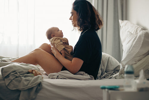 Mother holding baby on bed