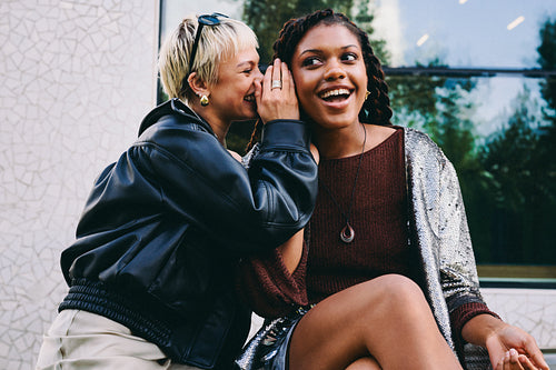 Whispering friend shares a secret with a woman