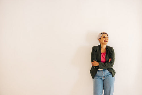 Young businesswoman laughing cheerfully against a wall