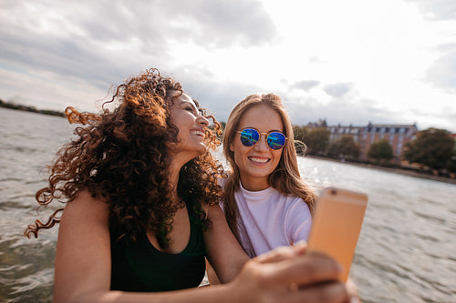 Beautiful young women taking selfie by the lake