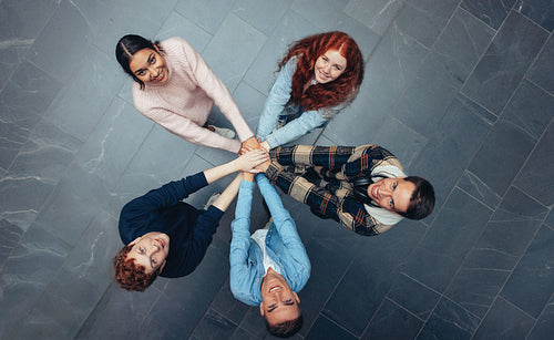 Diverse students with staked hands in college